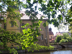 Das Wasserschloss vom Schloßpark aus gesehen, im Hintergrund die Berbisdorfer Kirche
